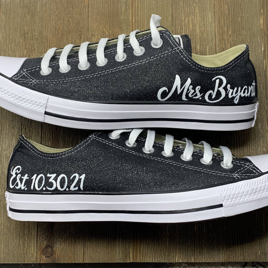 Mrs. painted on a pair of Black Glitter Converse with a wood floor background.