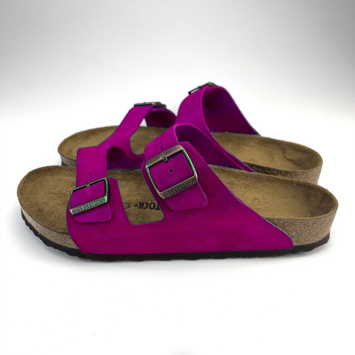 side view of hot pink magenta birkenstock sandals with buckles on a white floor