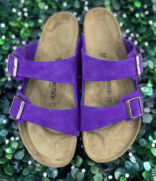 Purple Birkenstock Sandals sitting on a bridal greenery background