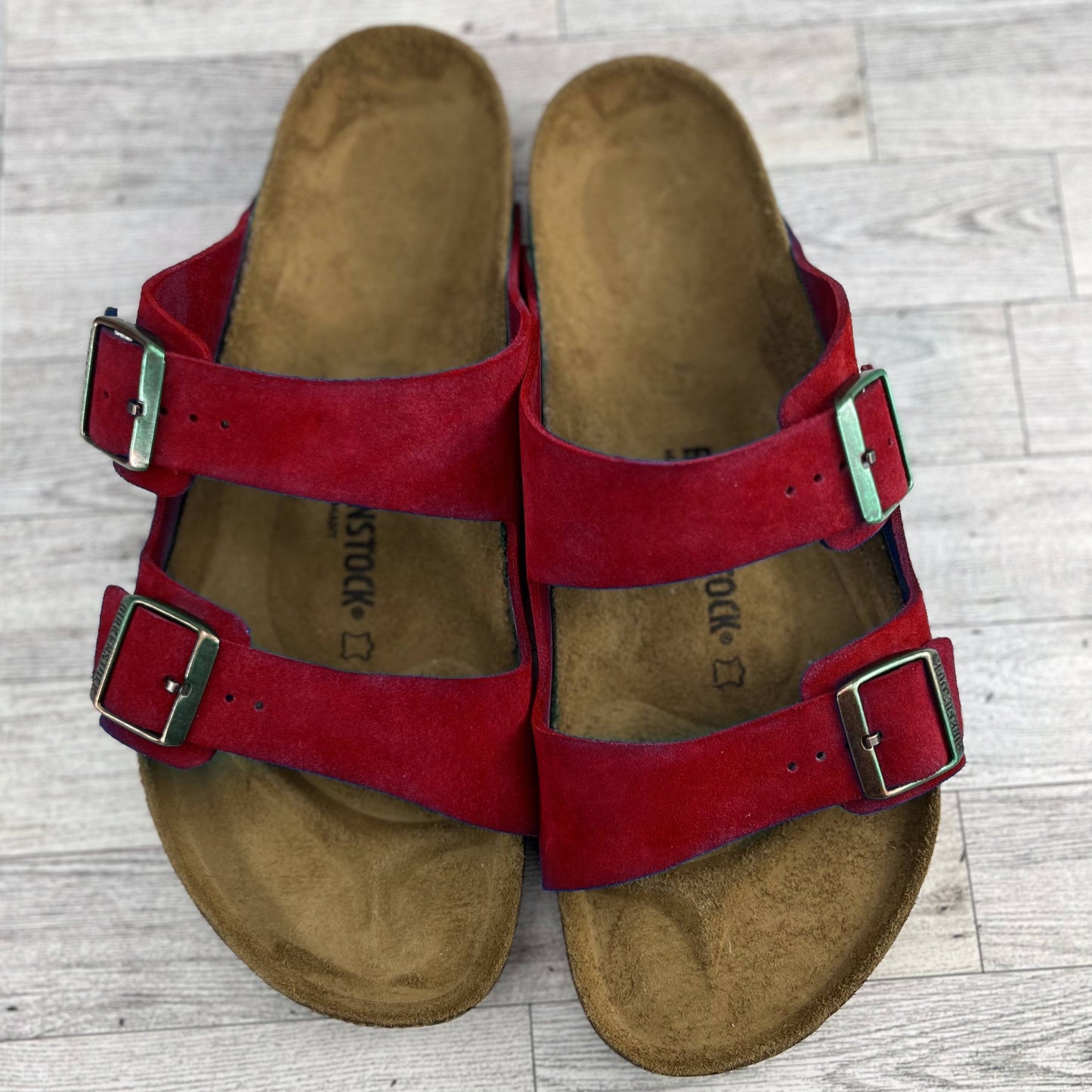 Red Arizona Birkenstock Sandals on grey wood floor