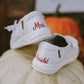 Back heels of white Hey Dude shoes with Mrs. Arnold painted on them. Shoes are sitting on a pumpkin for a fall wedding.